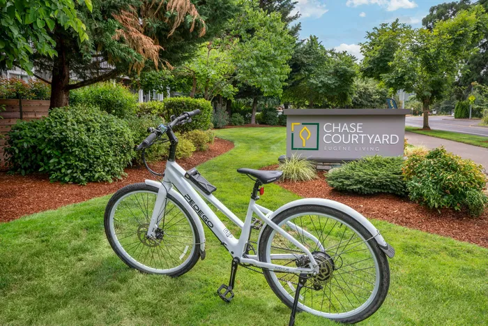 Inviting Chase Courtyard entrance with vibrant greenery and a modern bicycle, showcasing the essence of Eugene living.