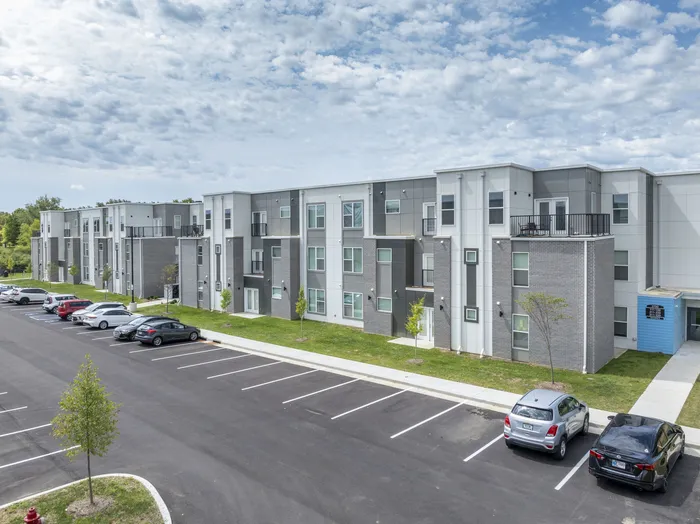 Modern apartment complex with sleek architecture, ample parking, and well-maintained landscaping under a clear sky. West Lafayette, Indiana. Near Purdue.