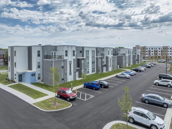 Modern apartment complex featuring sleek architecture, spacious balconies, and ample parking, set against a backdrop of a vibrant community.