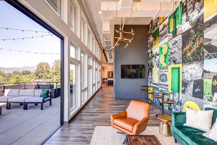 Vibrant lounge area with chic furnishings, colorful accent wall, and expansive windows opening onto a scenic terrace.