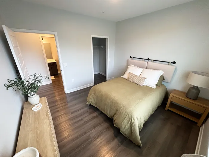 Inviting bedroom with modern decor, featuring a cozy bed, wooden floors, and ample natural light.