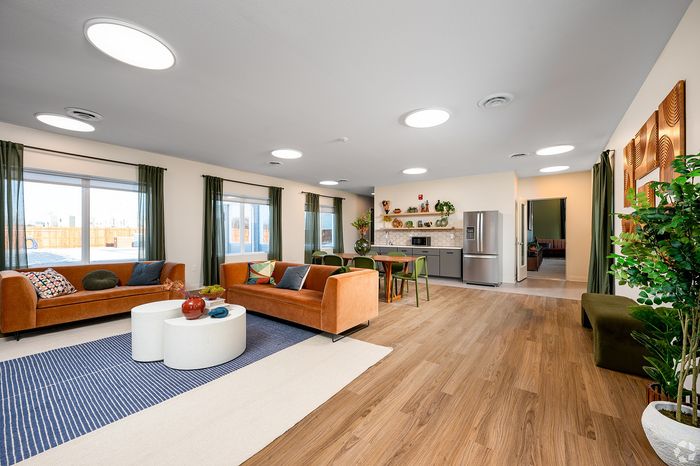 Modern open-concept living space featuring sleek hardwood floors, vibrant seating, and a stylish kitchen with stainless steel appliances.