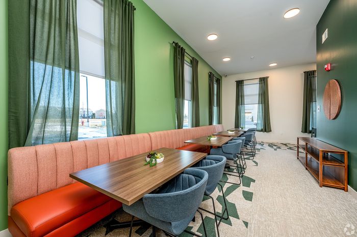 Chic modern dining area with elegant green walls, stylish wooden tables, and comfortable seating, ideal for gatherings.