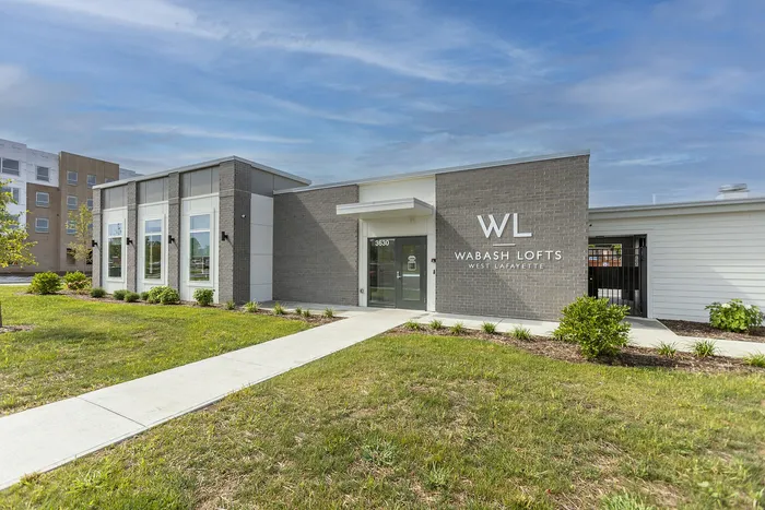 Contemporary exterior of Wabash Lofts in West Lafayette, showcasing stylish architecture and manicured landscaping under a vibrant sky.