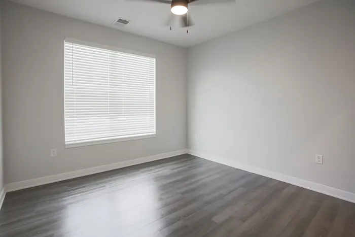 Bright and airy room with sleek hardwood floors and modern ceiling fan, perfect for a stylish and cozy living space.