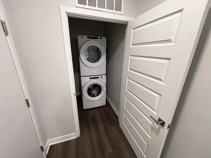 Modern laundry closet with stacked washer and dryer, featuring sleek design and efficient space utilization.