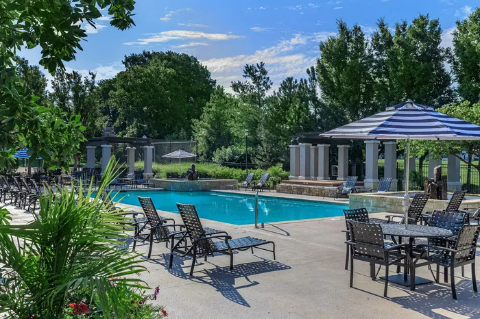Resort-style outdoor pool and hot tub with lounge chairs and umbrella tables at Corbin Crossing Overland Park KS