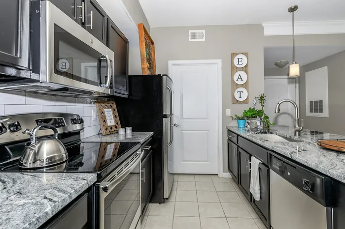 Modern apartment kitchen with granite countertops, stainless steel appliances, and pendant lighting at Corbin Crossing Overland Park KS