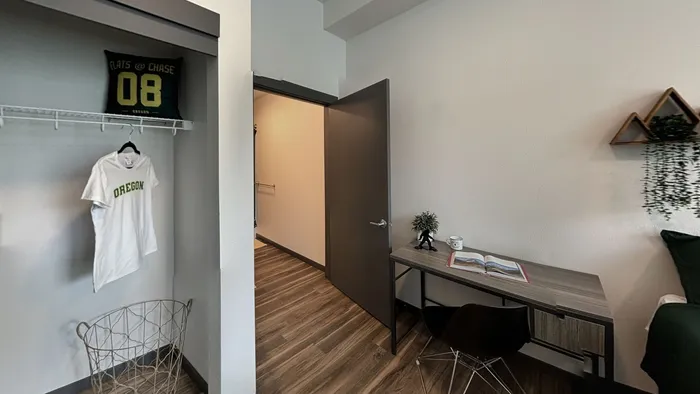 Bedroom with wooden floor, work desk, and open closet at The Flats at Chase in Eugene, OR