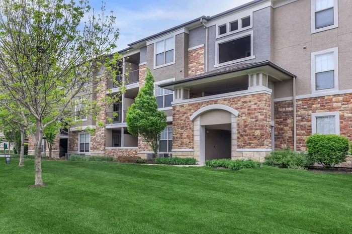 Corbin Crossing apartment building exterior with stone facade and green lawn in Overland Park KS