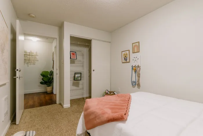 Furnished model bedroom with open closet and stylish wall art at Stadium Park in Eugene OR
