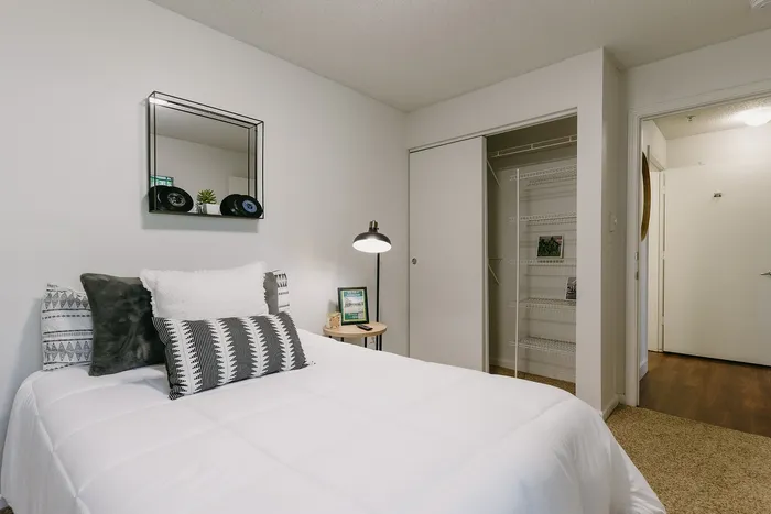 Furnished bedroom with plush bedding and open closet at Stadium Park in Eugene OR
