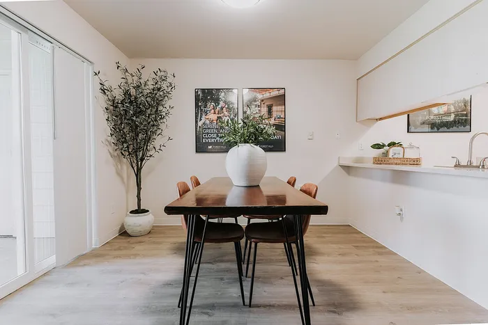 Inviting dining area with a modern wooden table, stylish chairs, and decorative potted plants, perfect for cozy gatherings.