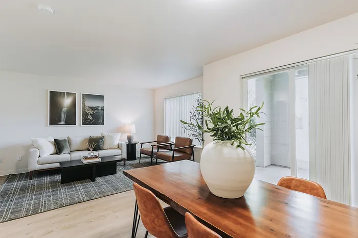 Elegant Forest Hills living room and dining area with modern decor, featuring a stylish sofa, comfortable chairs, and a large wood dining table with a decorative plant centerpiece.