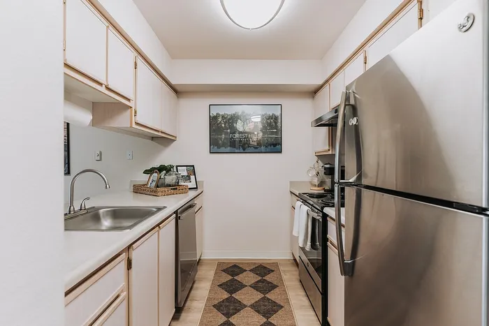 Inviting Forest Hills kitchen with stainless steel appliances, sleek countertops, and elegant cabinetry under soft, ambient lighting.