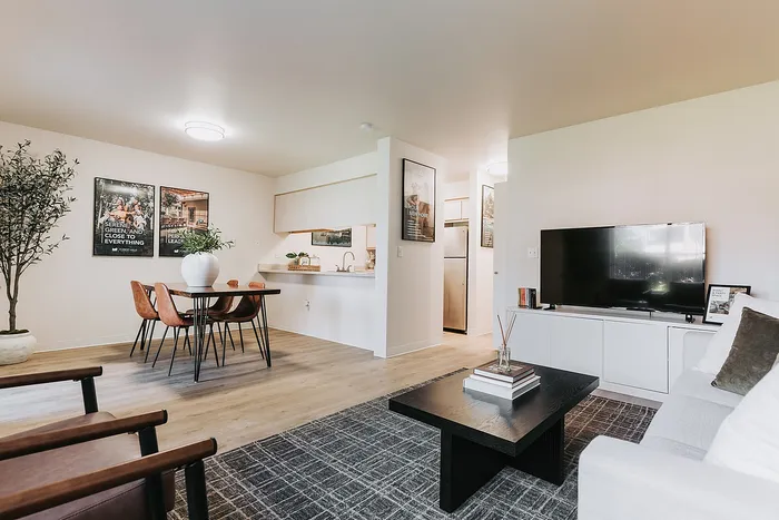 Modern open-concept living and dining area with stylish decor, large TV, and sleek furniture offering a warm, inviting ambiance located at Forest Hills.