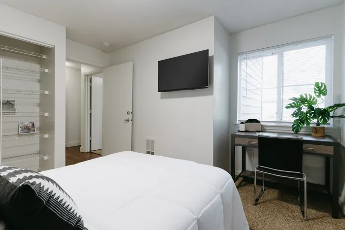 Furnished bedroom with wall-mounted TV and natural light at Stadium Park in Eugene OR