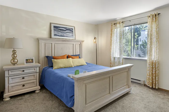 Canyon Springs apartment bedroom with cozy blue bedspread and large window with scenic views in Lynnwood WA
