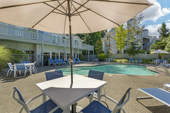 Canyon Springs heated outdoor pool with lounge chairs shaded tables and lush greenery in Lynnwood Washington