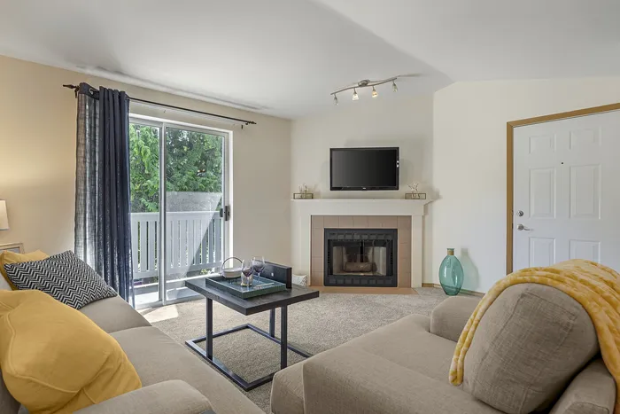 Canyon Springs apartment living room with cozy fireplace stylish decor and glass doors to leafy outdoor view in Lynnwood WA