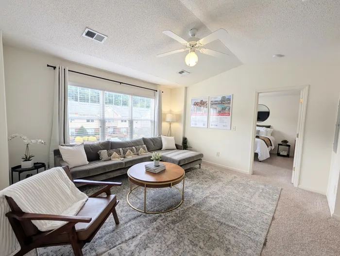 Spacious living room with plush sofa and natural light at University Suites apartments in Raleigh NC