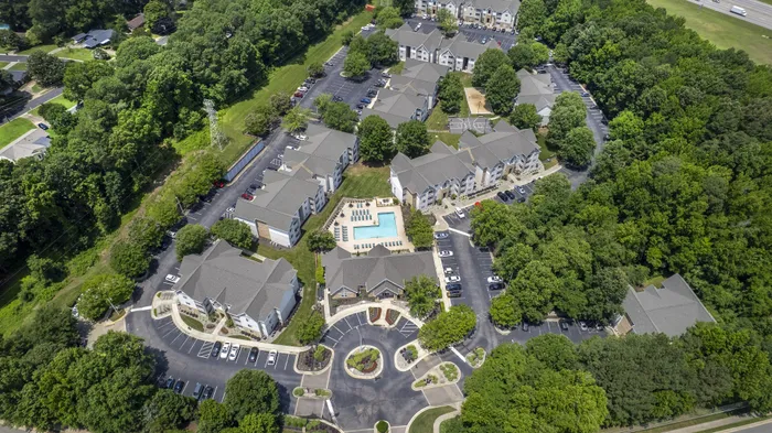 Aerial view of Village Green student living community surrounded by lush greenery with a central swimming pool and ample parking near NC State University in Raleigh NC