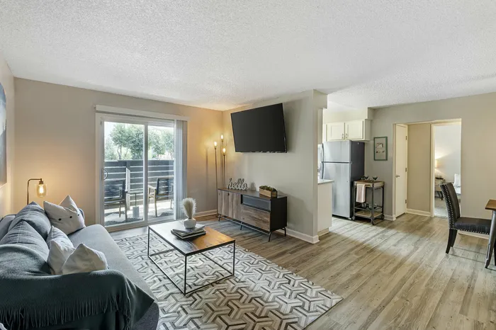 The Phoenix Reno living room with cozy sofa, large TV, and sliding doors to private patio in Reno NV