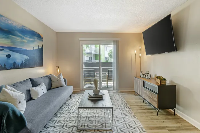 The Phoenix Reno living room with gray sofa, wall art, and natural light from sliding glass door in Reno NV