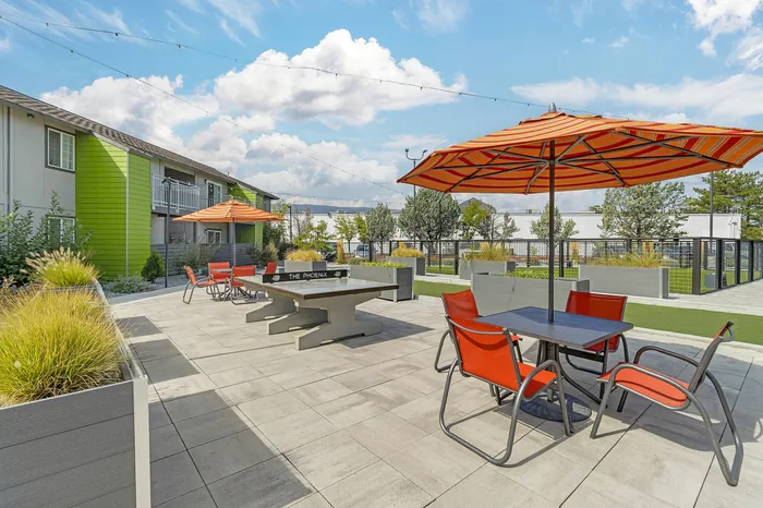 The Phoenix Reno outdoor lounge patio with orange umbrellas, modern seating, and lush greenery in Reno NV