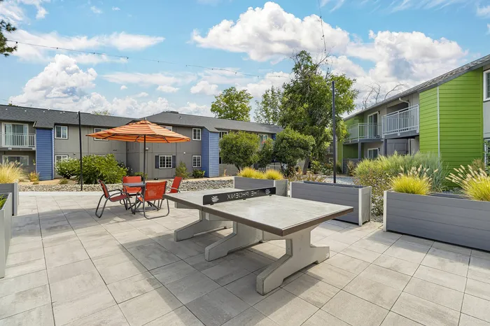 The Phoenix Reno outdoor patio with ping pong table, orange umbrella, and lush landscaping in Reno NV