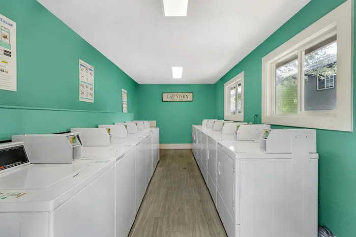 The Phoenix Reno 24-hour laundry facility with washing machines against teal wall and natural light in Reno NV