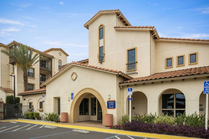Highlander at North Campus Mediterranean-style leasing office with arched entryway, terracotta tiles, and lush landscaping in Riverside CA