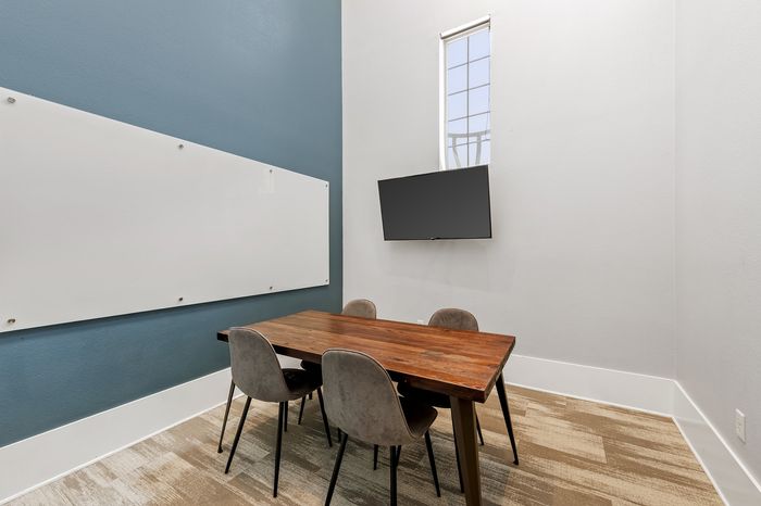 Highlander at North Campus study room with wooden table, plush chairs, whiteboard, and wall-mounted TV in Riverside CA
