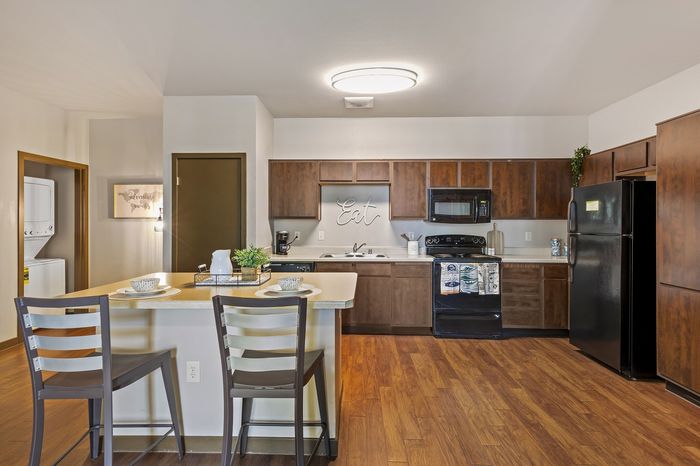 Highlander at North Campus model kitchen with wooden cabinetry, spacious countertop, and cozy breakfast bar in Riverside CA
