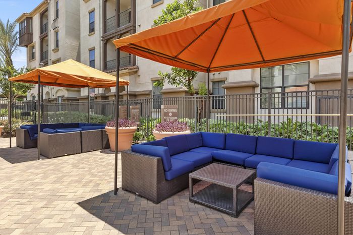Highlander at North Campus outdoor lounge with vibrant blue cushioned seating and orange canopies in Riverside CA