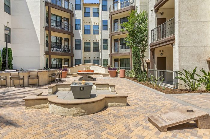 Highlander at North Campus outdoor courtyard with fire pit and seating area surrounded by lush greenery in Riverside CA