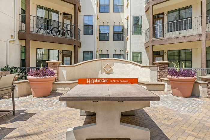 Highlander at North Campus vibrant courtyard with modern balconies, lush planters, and outdoor ping pong and seating area in Riverside CA