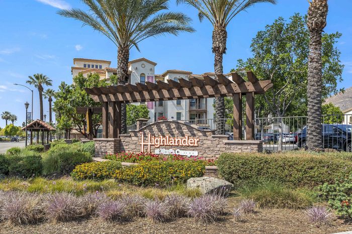 Highlander at North Campus monument sign entrance with lush landscaping, stone elements, and palm trees in Riverside CA