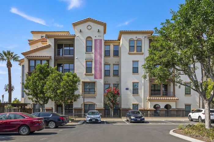 Highlander at North Campus Mediterranean-style apartment exterior with lush greenery and parking in Riverside CA