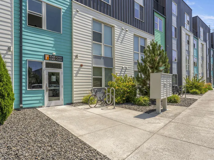 Republic on Main apartment exterior with colorful siding and lush landscaping, featuring bicycle racks and convenient mailbox access.