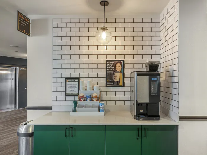 Republic on Main coffee station with modern espresso machine against a stylish white subway tile wall, offering a perfect spot for residents to enjoy a fresh brew.