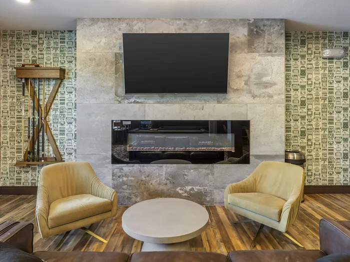 Republic on Main clubhouse living room with stylish yellow armchairs, sleek fireplace, wall-mounted TV, and artistic wallpaper in Moscow, ID