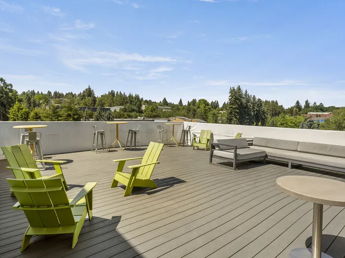 Republic on Main rooftop terrace with vibrant green chairs, cozy seating, and panoramic views of lush greenery under a bright blue sky in Moscow, ID