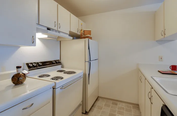 Cozy kitchen with modern white cabinetry, sleek countertops, and classic appliances providing a functional and inviting cooking space at Maplewood Park apartment community in Renton, WA.