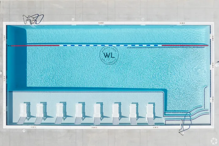 Aerial view of a luxurious swimming pool with crisp blue water, featuring elegant lounge chairs on a sun-drenched deck, ideal for relaxation.