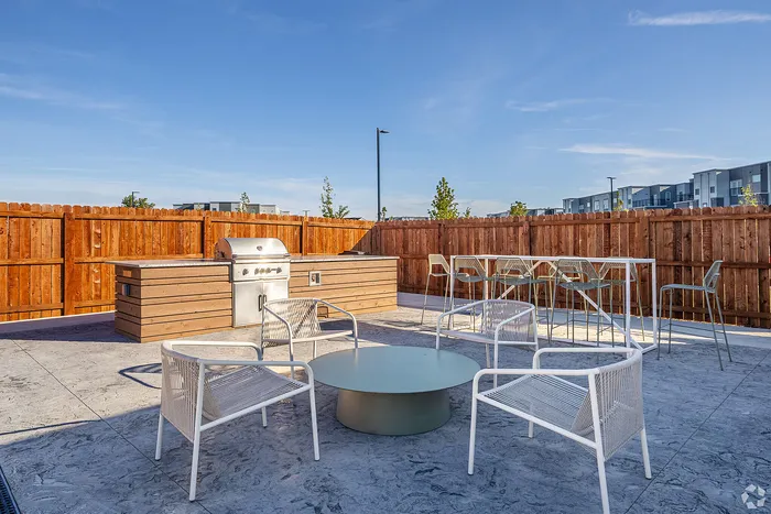 Modern outdoor patio featuring a sleek grill, stylish seating, and a private fence, ideal for entertaining.