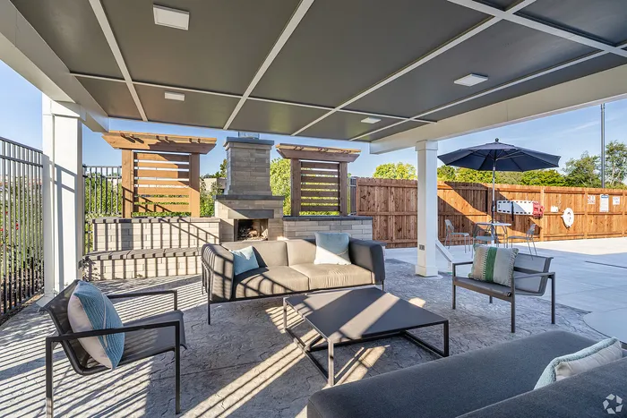 Chic outdoor living space featuring a modern covered patio with cozy seating, stylish fireplace, and inviting dining area.