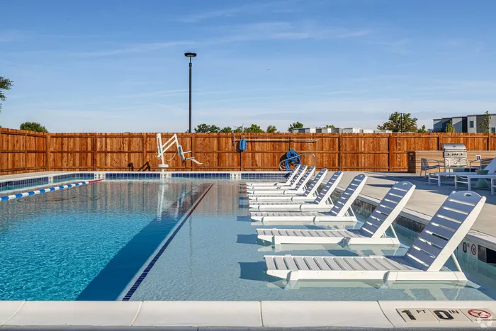 Elegant outdoor pool area with modern sun loungers and clear blue water, perfect for relaxation and leisure.