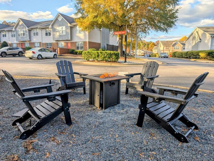 Charming outdoor seating area with four Adirondack chairs surrounding a cozy fire pit, set against a backdrop of a picturesque residential neighborhood.