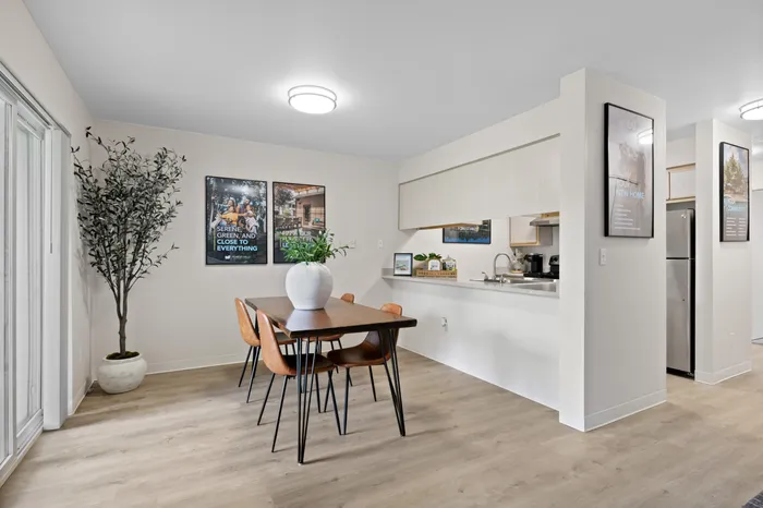 Contemporary dining area with a sleek wooden table, stylish chairs, and a modern kitchen, featuring elegant decor and natural light.